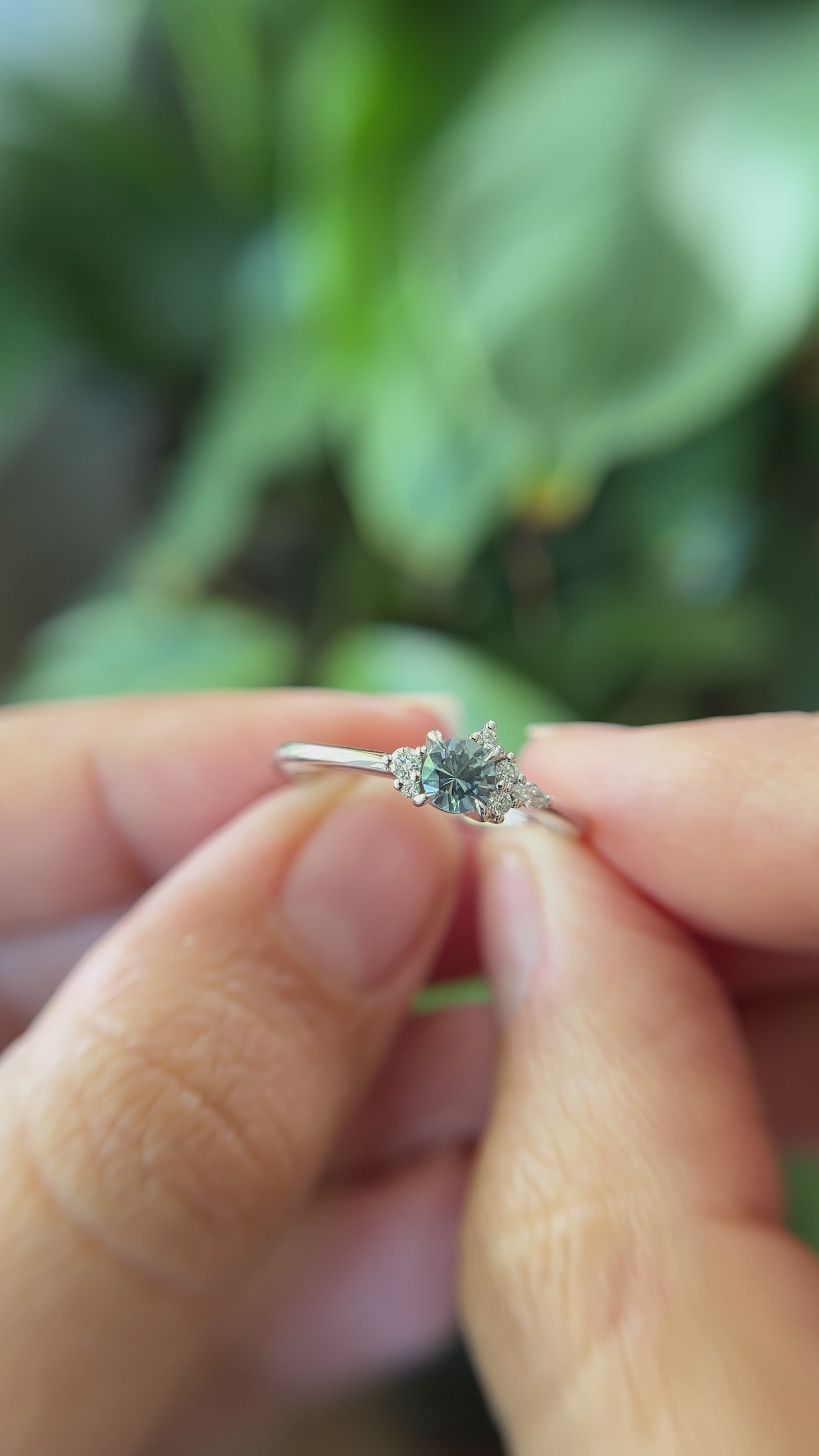 0.35ct round blue sapphire and natural diamond constellation engagement ring in 14k white gold, held in hands showing gemstone colour and faceting