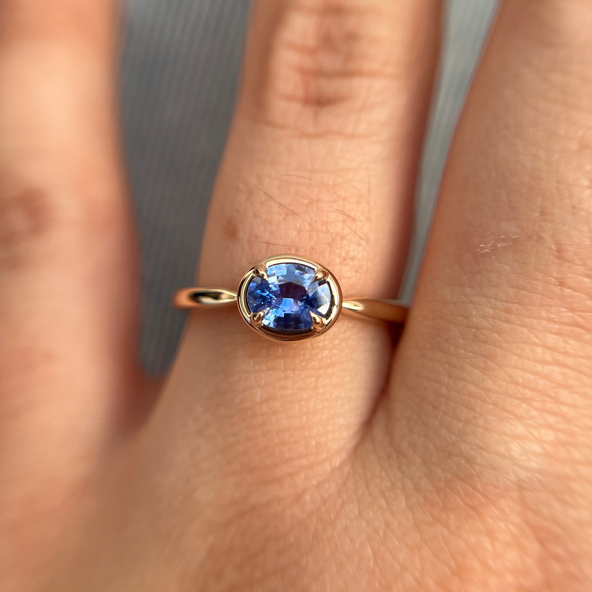 0.61ct unheated oval royal blue sapphire solitaire ring in 14k yellow gold, worn on hand showing stone colour and gold frame setting