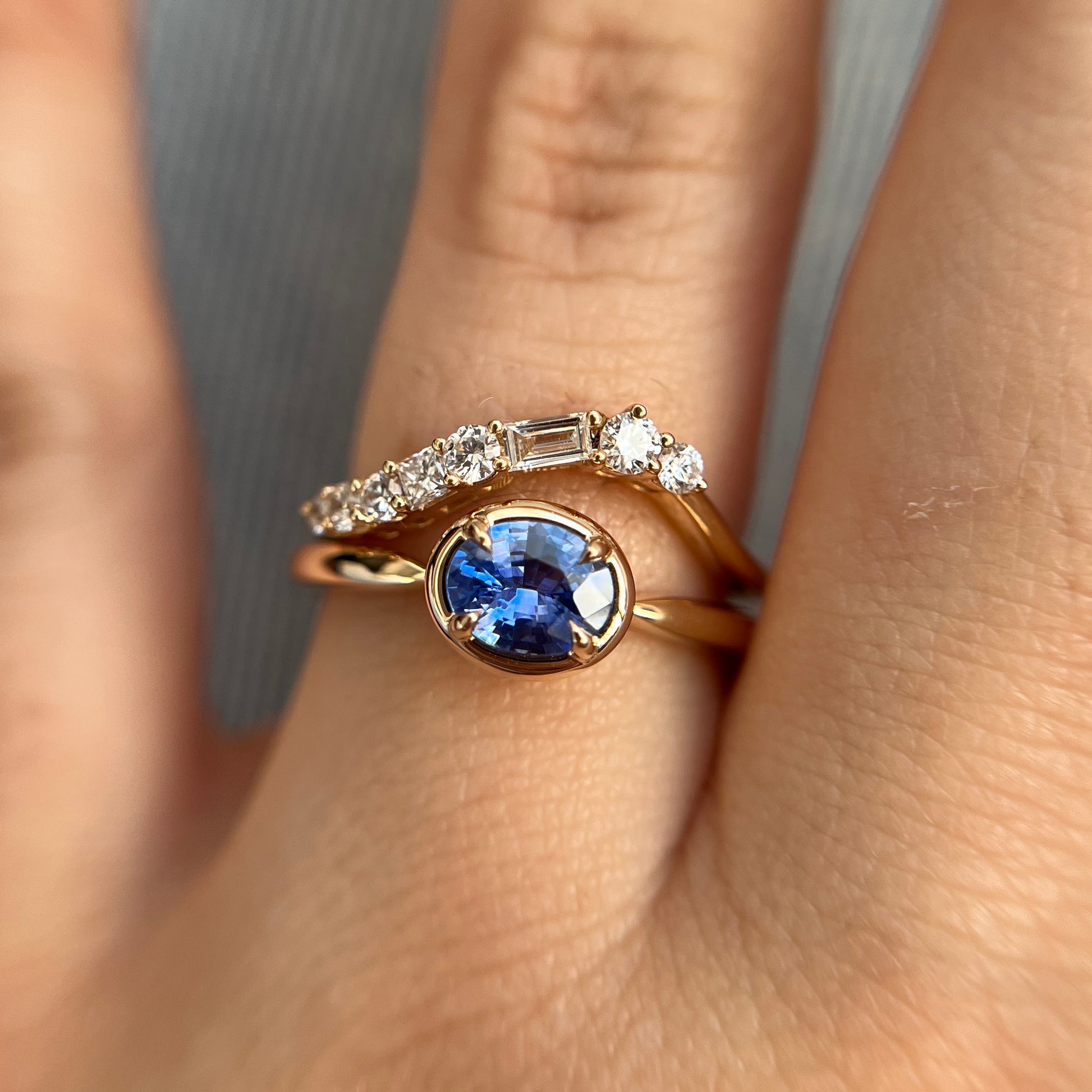 0.61ct unheated oval royal blue sapphire solitaire ring in 14k yellow gold, styled with matching diamond wedding band, worn on hand