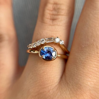 0.61ct unheated oval royal blue sapphire solitaire ring in 14k yellow gold, styled with matching diamond wedding band, worn on hand