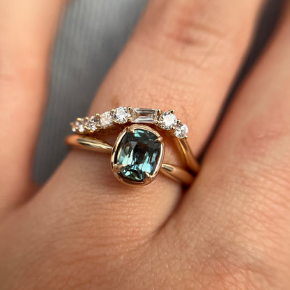 1.10ct elongated cushion cut teal sapphire solitaire ring in 14k yellow gold, styled with matching diamond wedding band, worn on hand