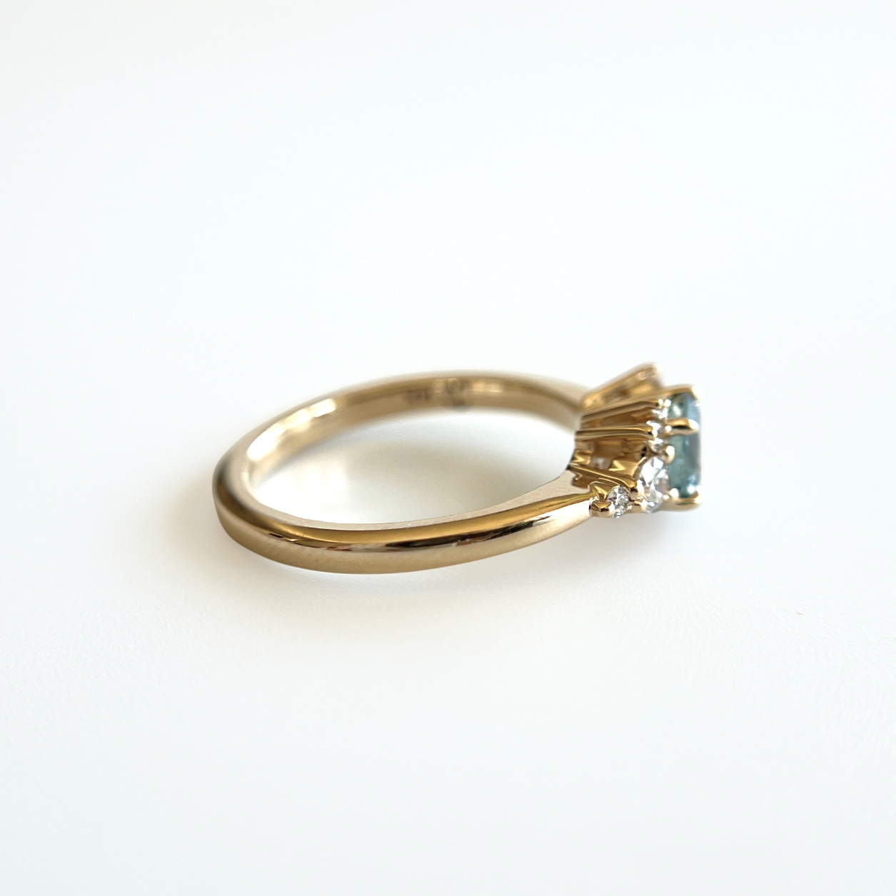 Bague de fiançailles en saphir sarcelle et diamants en or jaune 14k, vue de profil montrant la largeur du corps de bague et la hauteur du serti