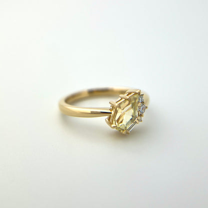 1.07ct shield cut light yellow Sri Lankan sapphire and diamond ring in 18k yellow gold, angled view showing eagle claw setting and band detail