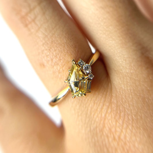 1.07ct shield cut light yellow Sri Lankan sapphire and diamond ring in 18k yellow gold, worn on hand showing stone colour and eagle claw setting