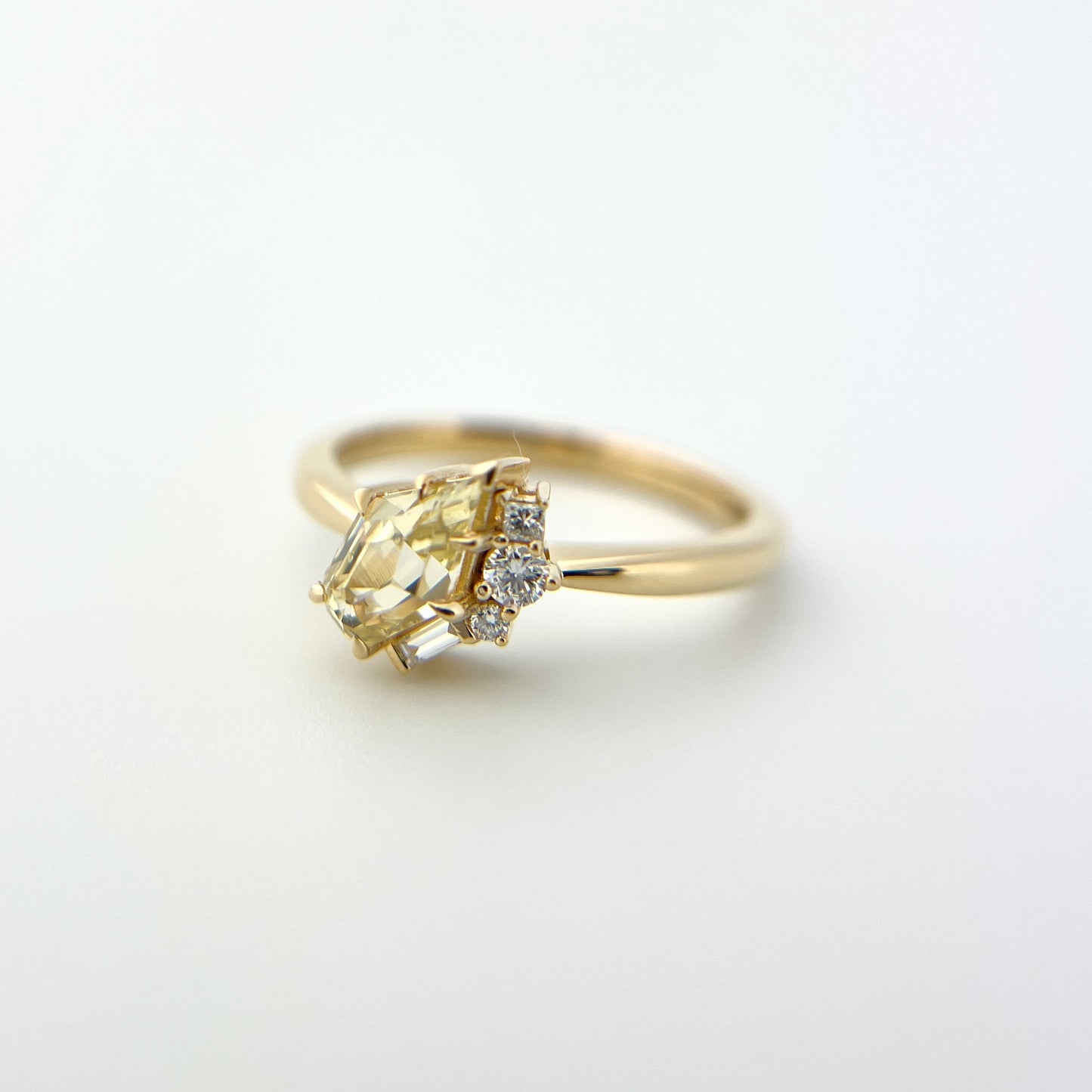 1.07ct shield cut light yellow Sri Lankan sapphire and diamond ring in 18k yellow gold, side view showing band profile and diamond accent detail