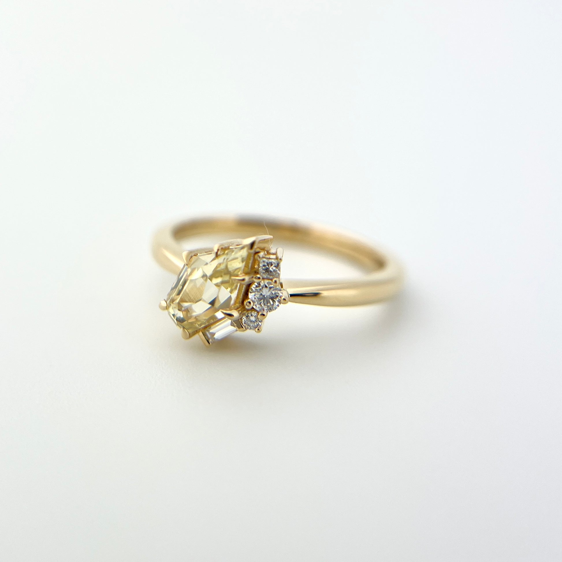1.07ct shield cut light yellow Sri Lankan sapphire and diamond ring in 18k yellow gold, side view showing band profile and diamond accent detail